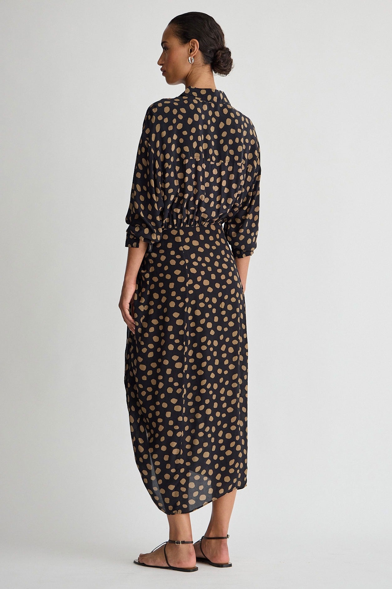 Woman wearing a long, patterned dress on a plain background