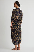 Woman wearing a long, patterned dress on a plain background