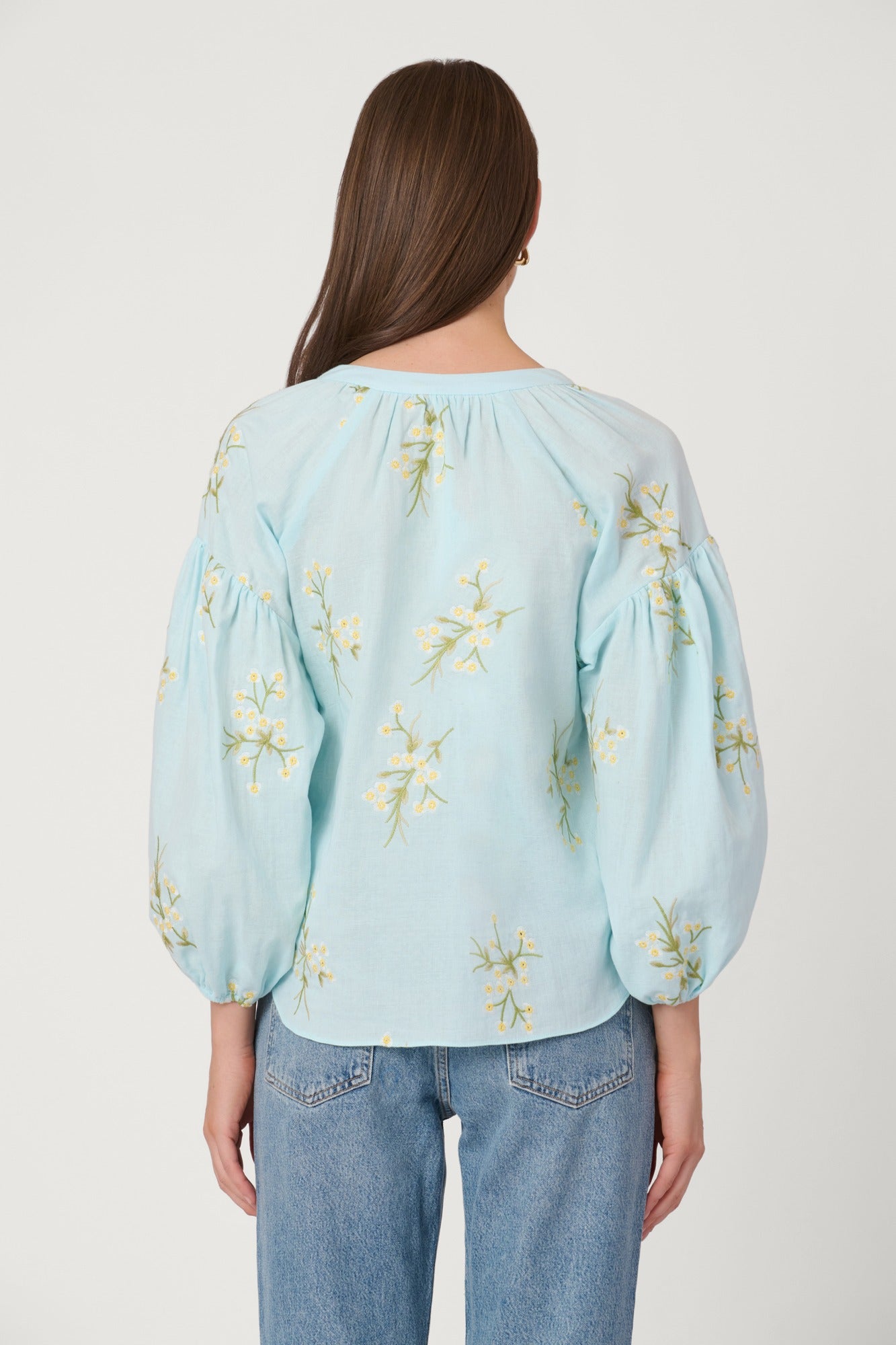 Light blue blouse with floral embroidery worn by a person on a plain background