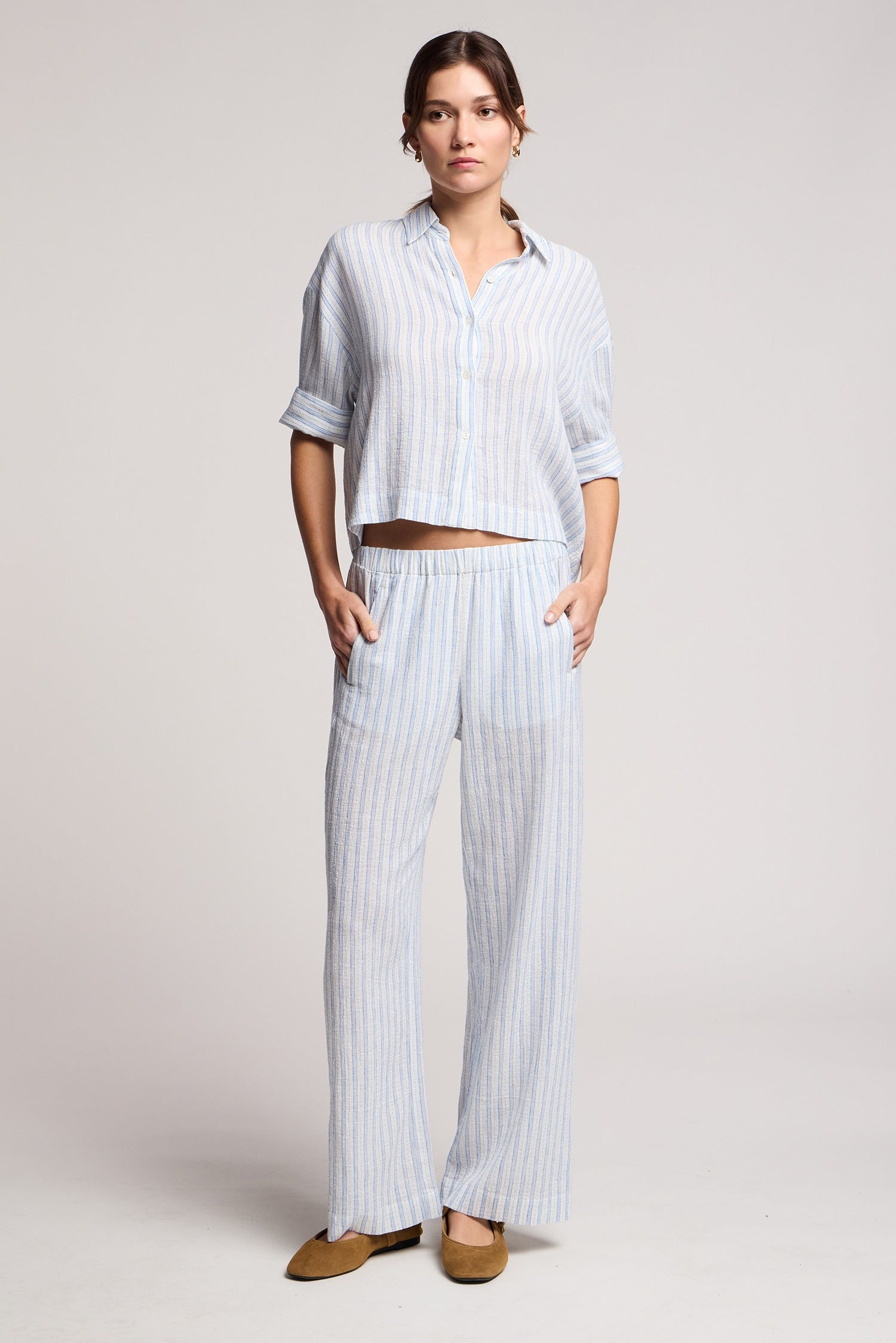 Woman wearing a light blue striped outfit on a plain background