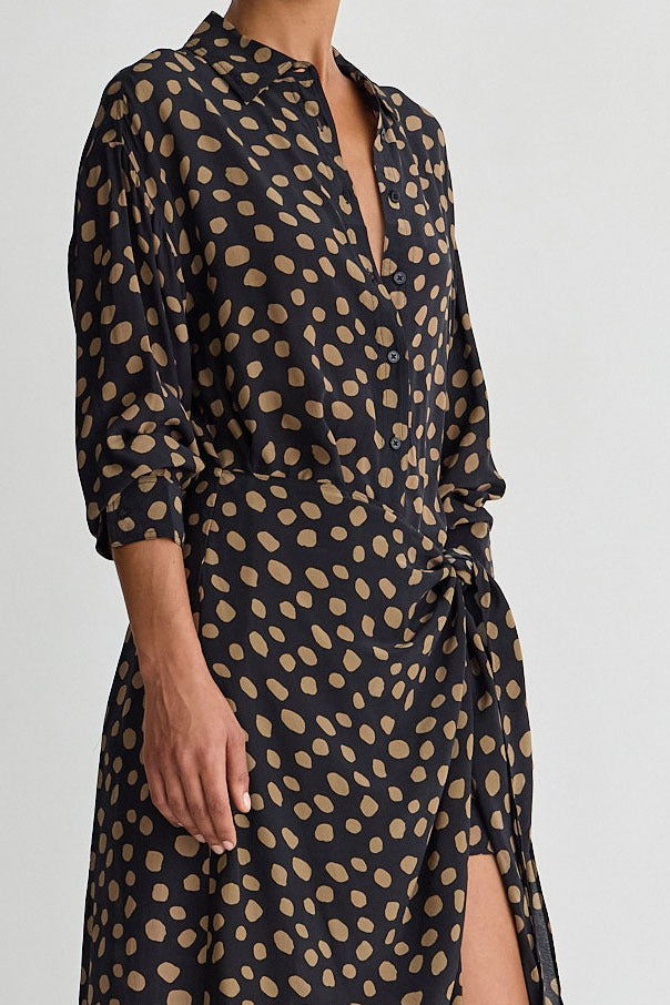 Black dress with gold polka dot pattern on a plain background