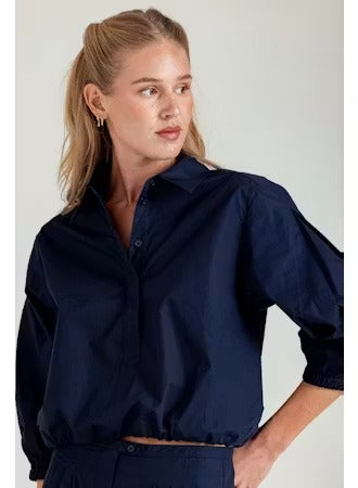 Woman wearing a navy blue shirt with a plain background