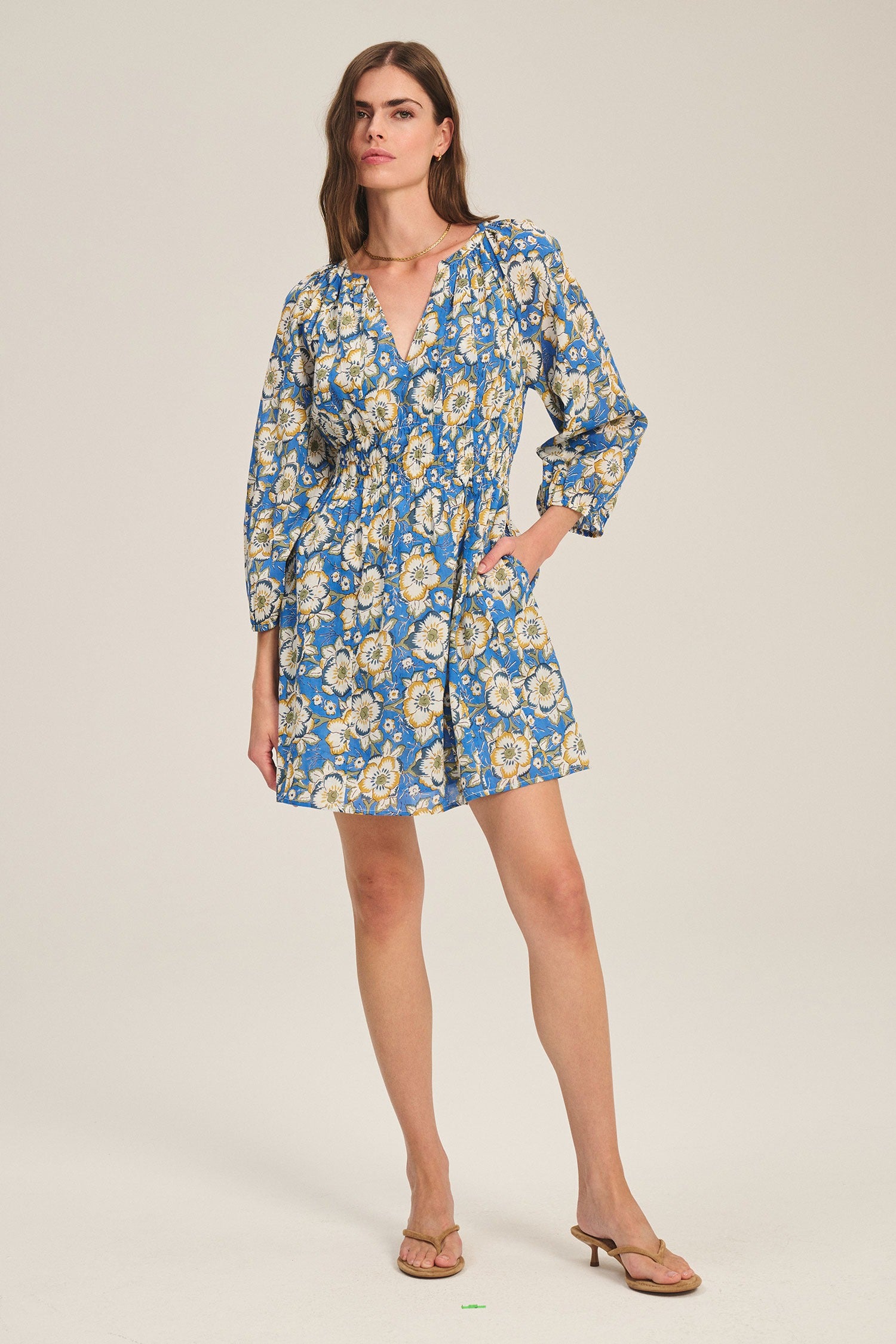 Woman wearing a blue floral dress on a beige background