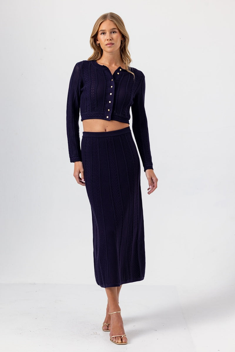 Woman wearing a navy ribbed knit outfit on a white background