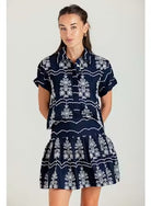 Woman wearing a navy dress with white patterns on a plain background