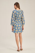 Woman wearing a blue floral dress on a beige background