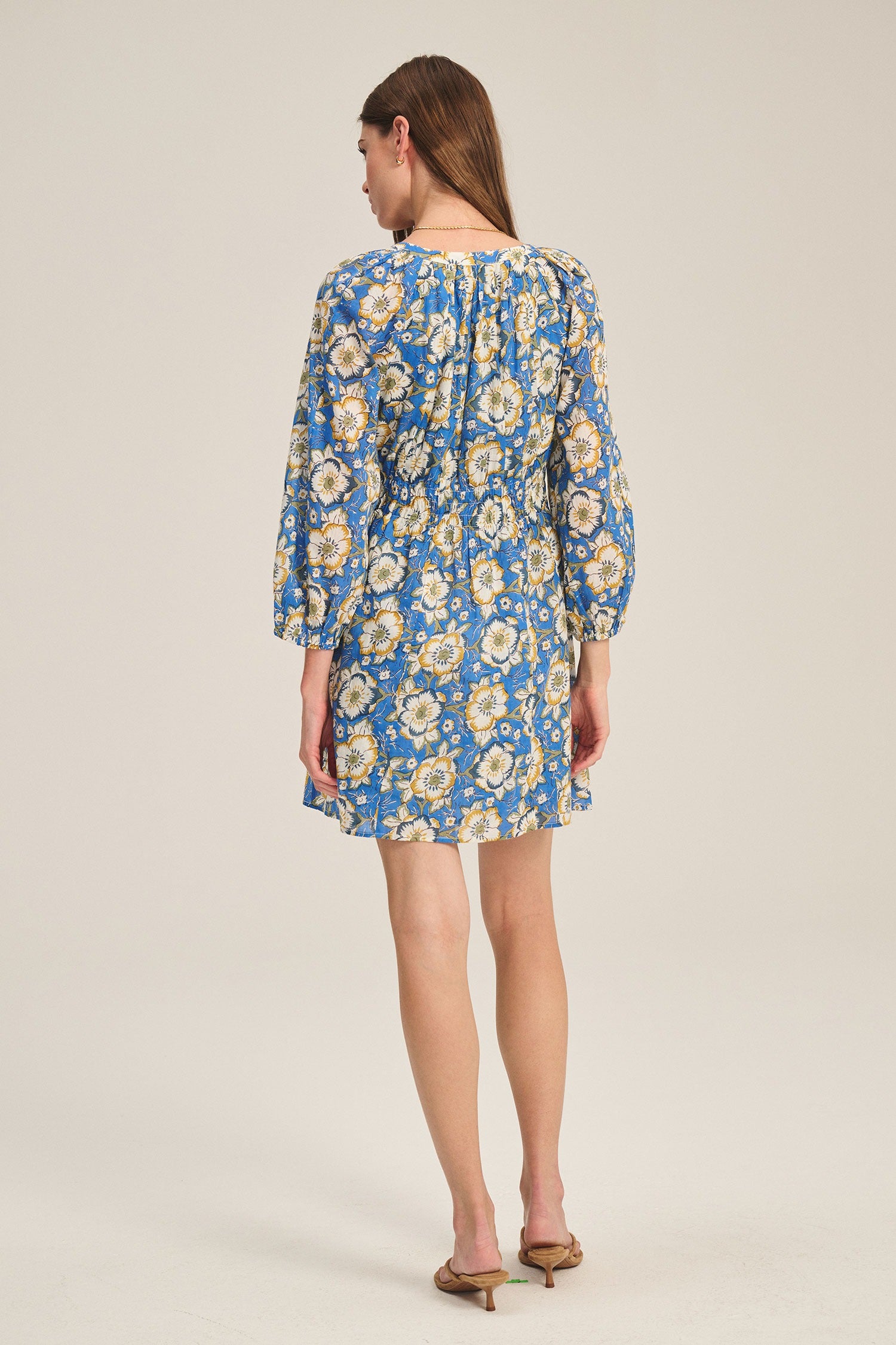 Woman wearing a blue floral dress on a beige background