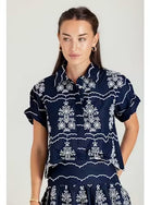 Woman wearing a navy blue dress with white floral patterns on a plain background