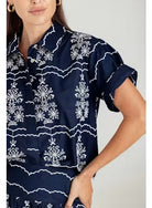 Navy blue shirt with white floral pattern worn by a person on a light gray background