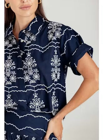 Navy blue shirt with white floral pattern worn by a person on a light gray background