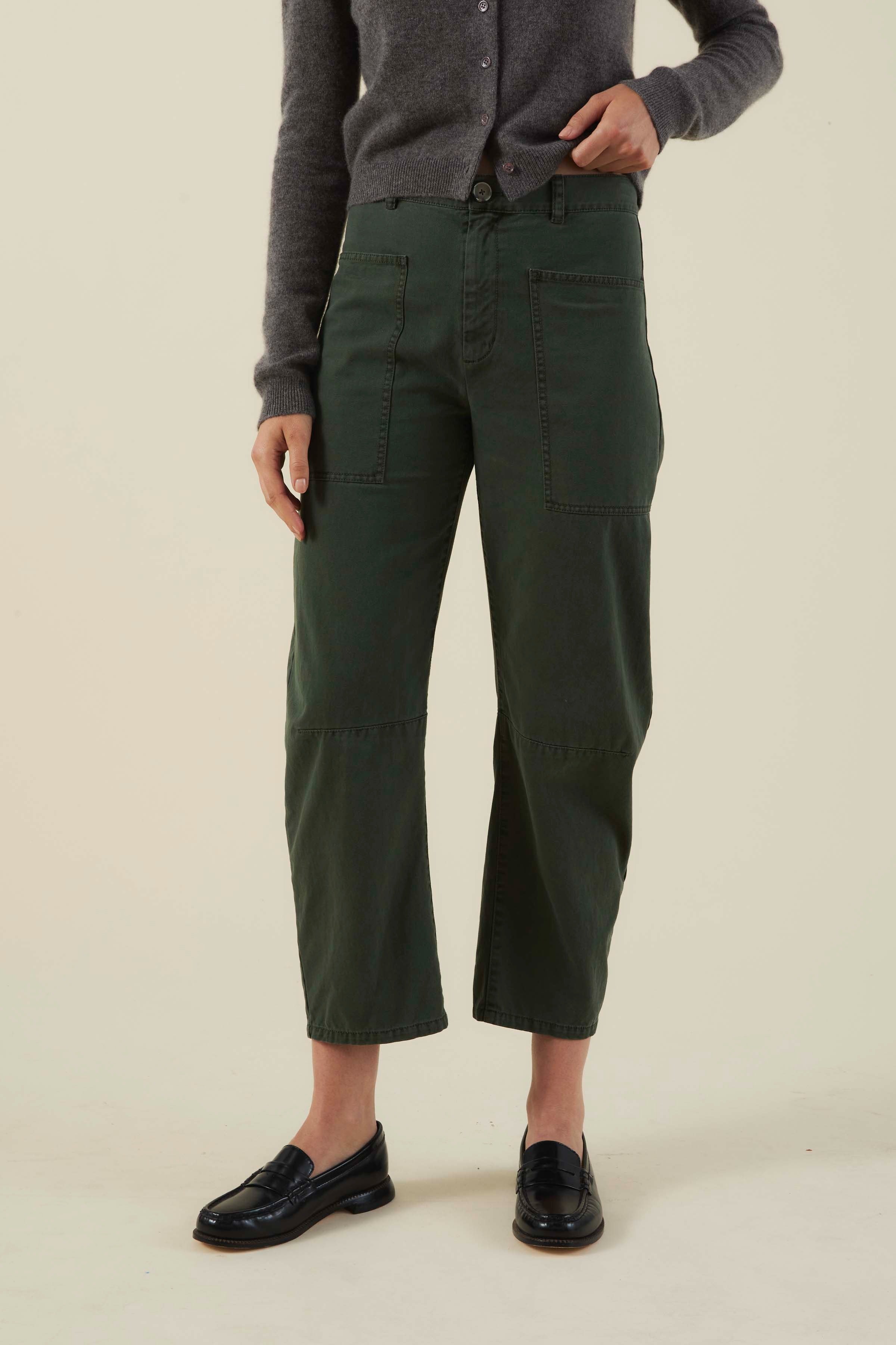 Person wearing green cargo pants and a gray sweater on a beige background