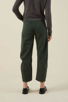 Person wearing green pants and a gray sweater on a beige background