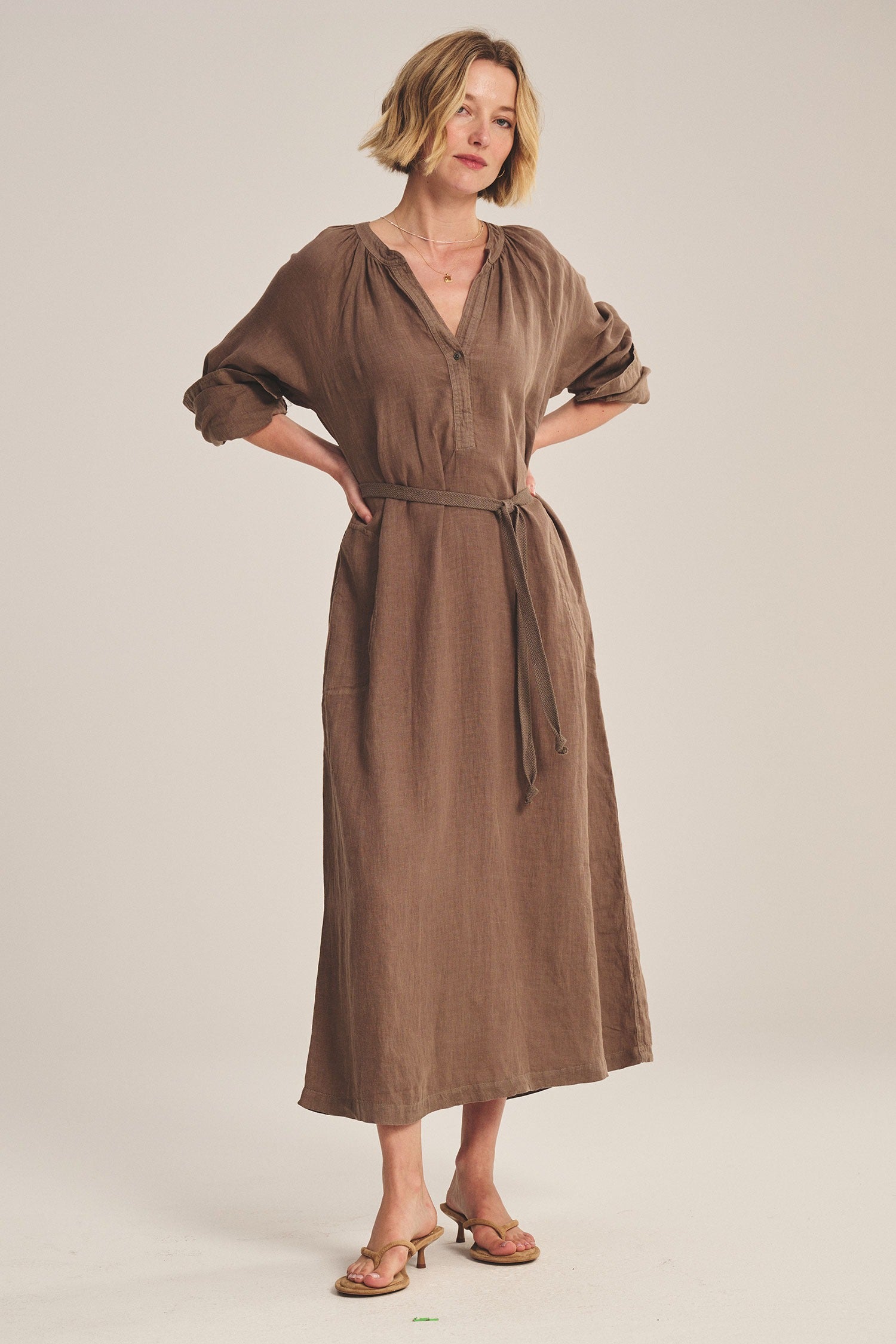 Woman wearing a brown dress against a plain background