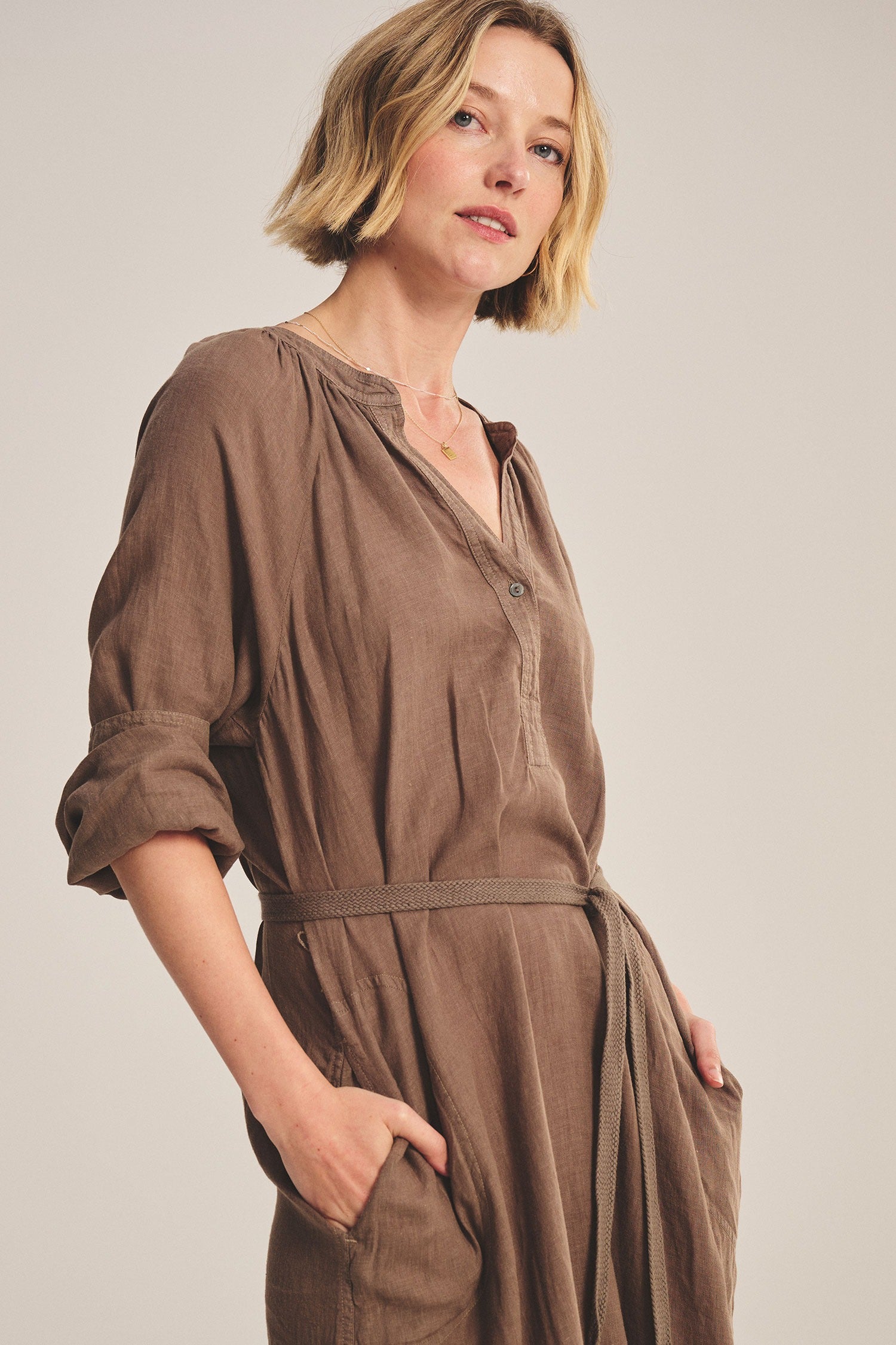 Woman wearing a brown dress against a plain background
