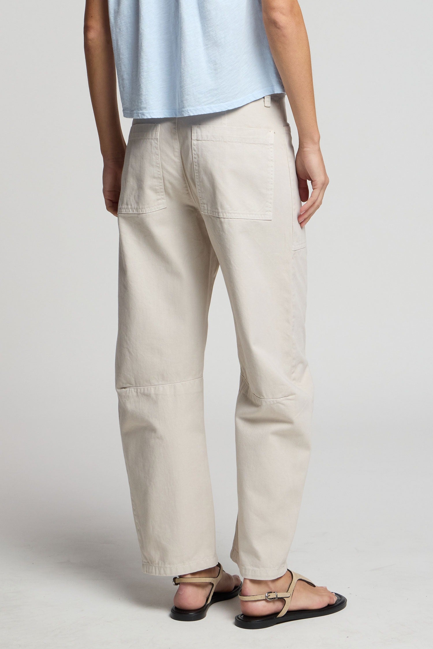 Person wearing light-colored pants and a light blue top on a plain background