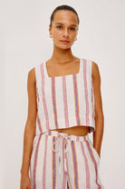 Woman wearing a sleeveless striped top and pants on a plain background