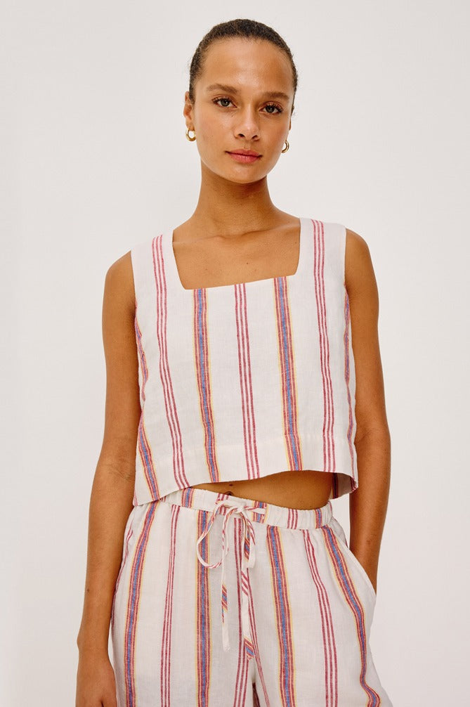 Woman wearing a sleeveless striped top and pants on a plain background