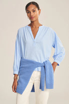 Woman wearing a light blue wrap-style top with a beige background