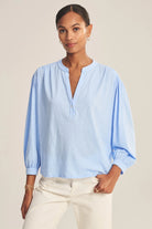 Woman wearing a light blue blouse with a neutral background