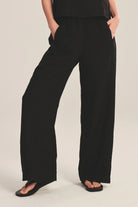 Person wearing black wide-leg pants on a plain background