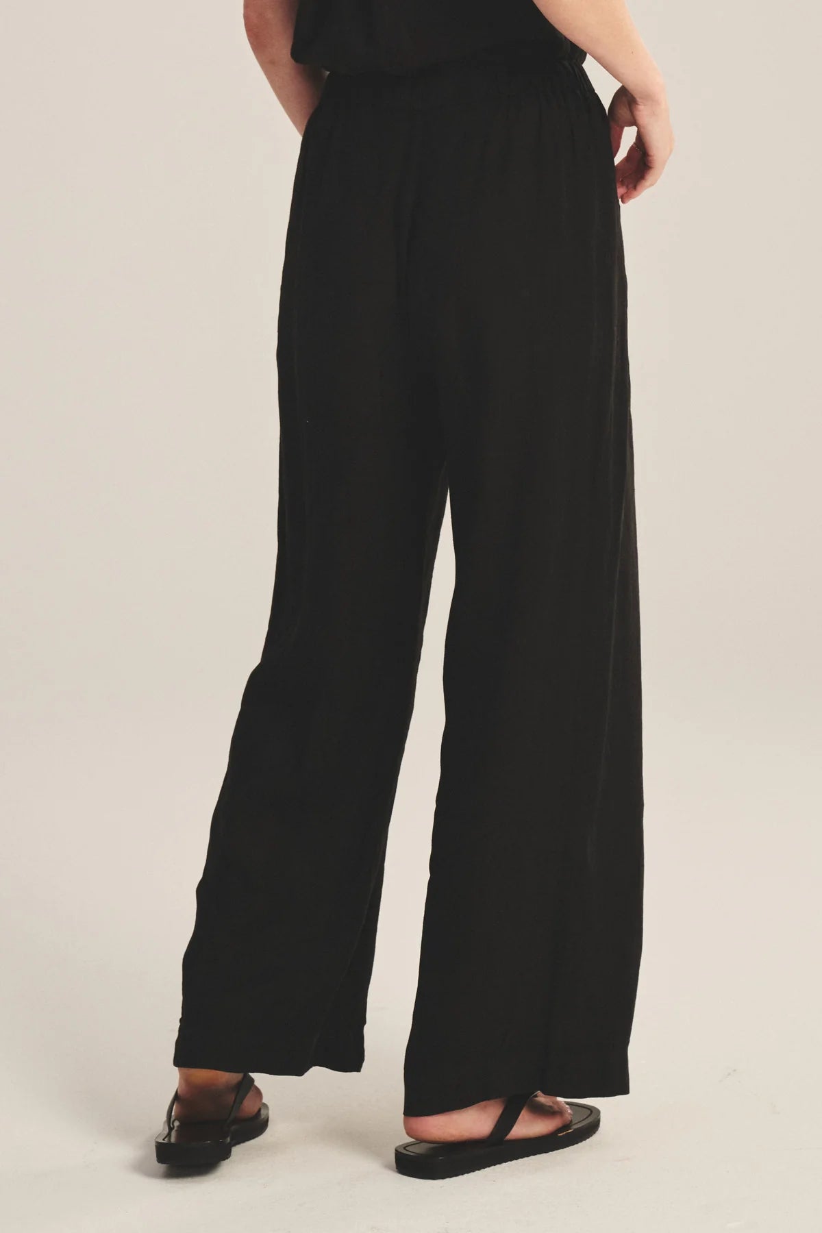 Person wearing black wide-leg pants on a plain background