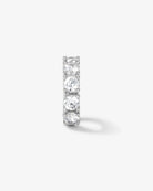 A slim silver-toned eternity ring featuring five round-cut clear stones set in a prong setting, shown against a light gray background with a soft shadow.