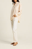 Person wearing a light-colored shirt and white pants on a plain background