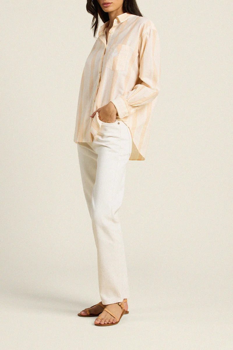 Person wearing a light-colored shirt and white pants on a plain background