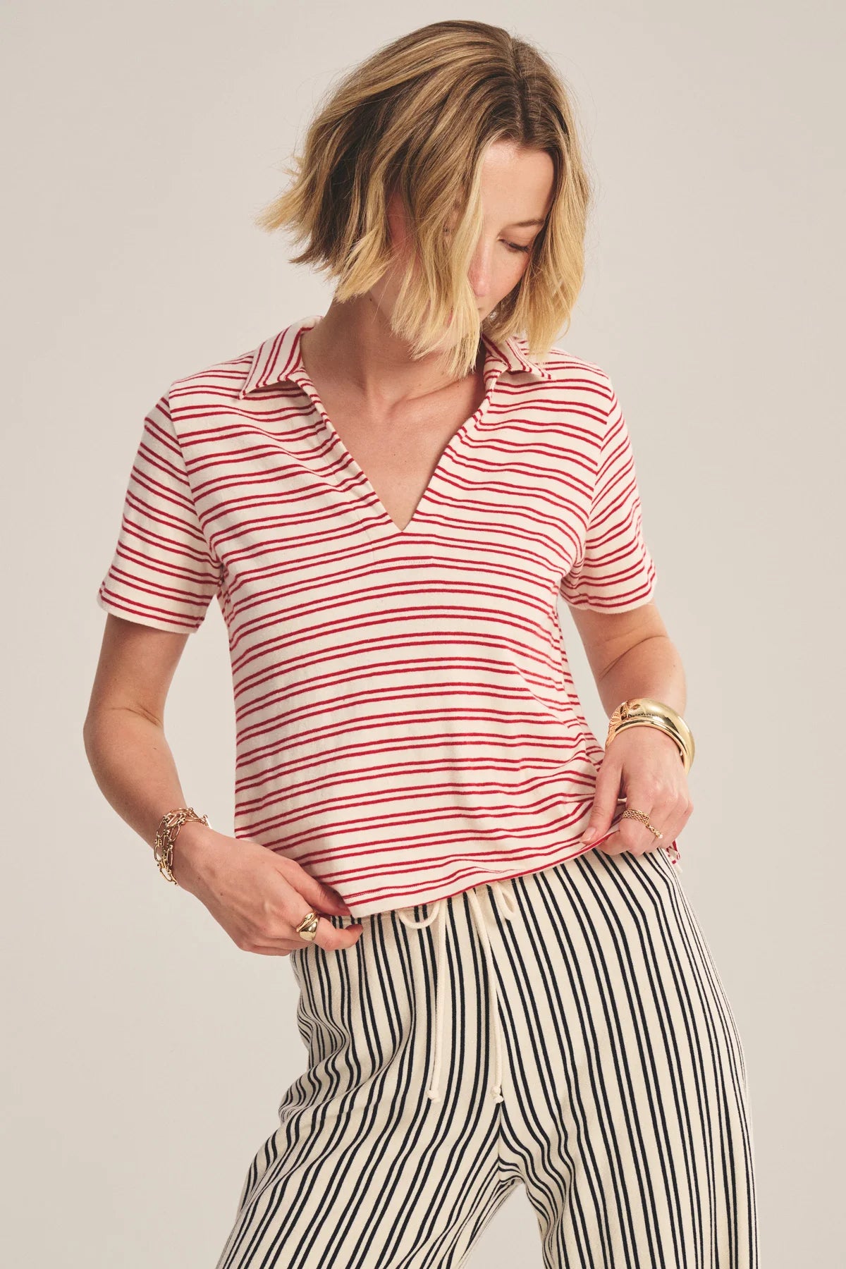 Woman wearing a red and white striped shirt and black and white striped pants on a plain background