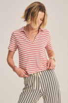 Woman wearing a red and white striped shirt and black and white striped pants on a plain background