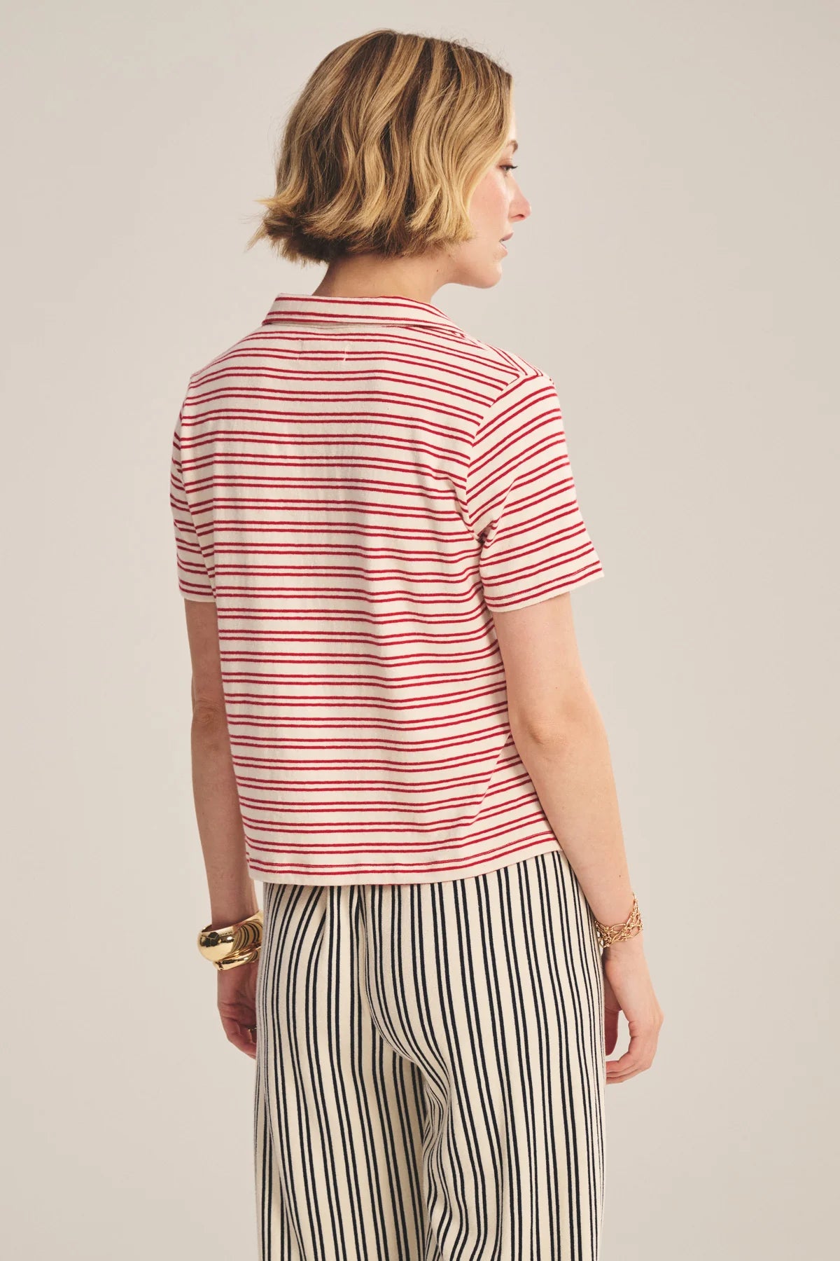 Woman wearing a red and white striped shirt and black and white striped pants on a beige background