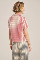 Woman wearing a red and white striped shirt and black and white striped pants on a beige background