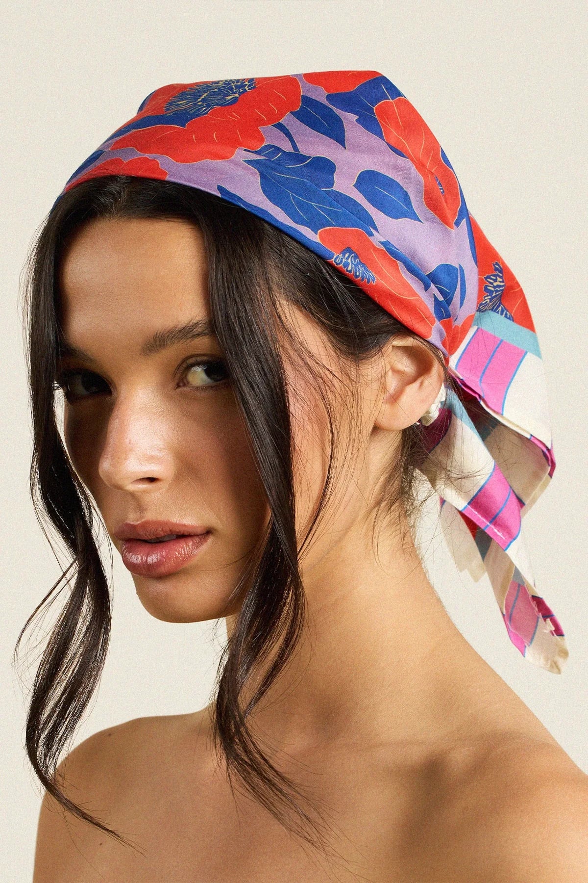 Woman wearing a colorful headscarf with a neutral background
