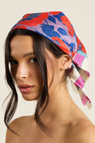 Woman wearing a colorful headscarf with a neutral background