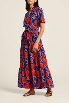 Woman wearing a red and blue floral dress on a beige background
