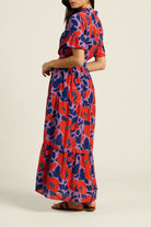 Woman wearing a colorful floral dress on a beige background