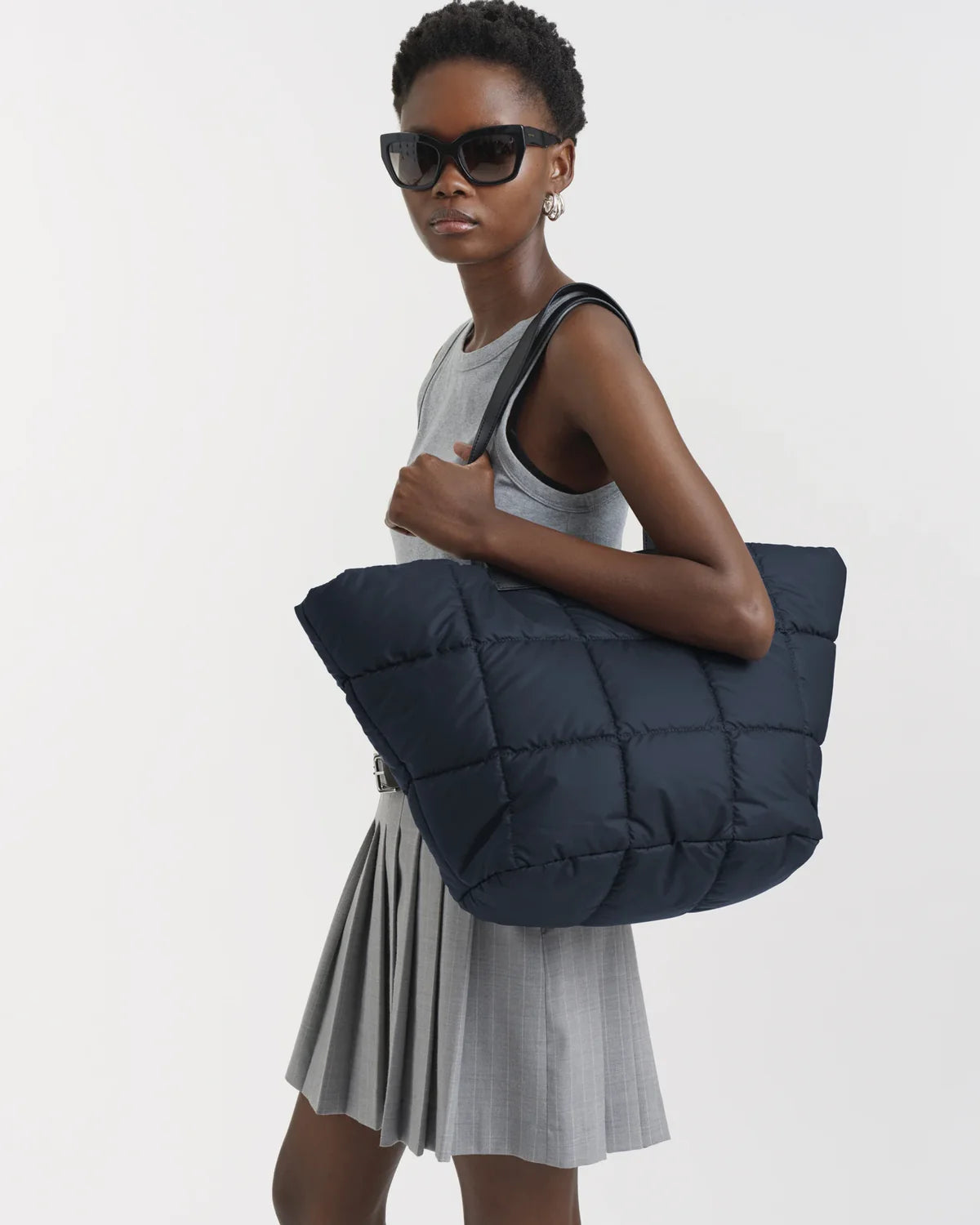 Woman holding a navy blue puffer bag against a white background