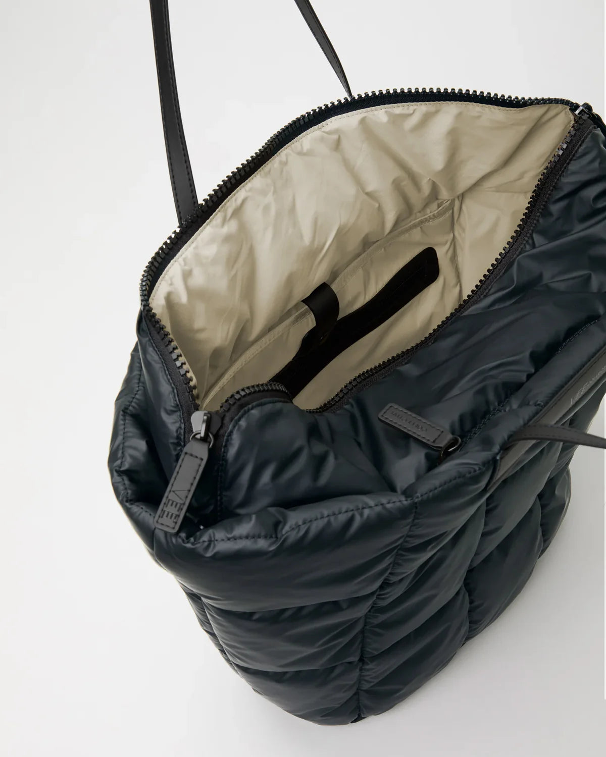 Black quilted bag with beige interior on a white background