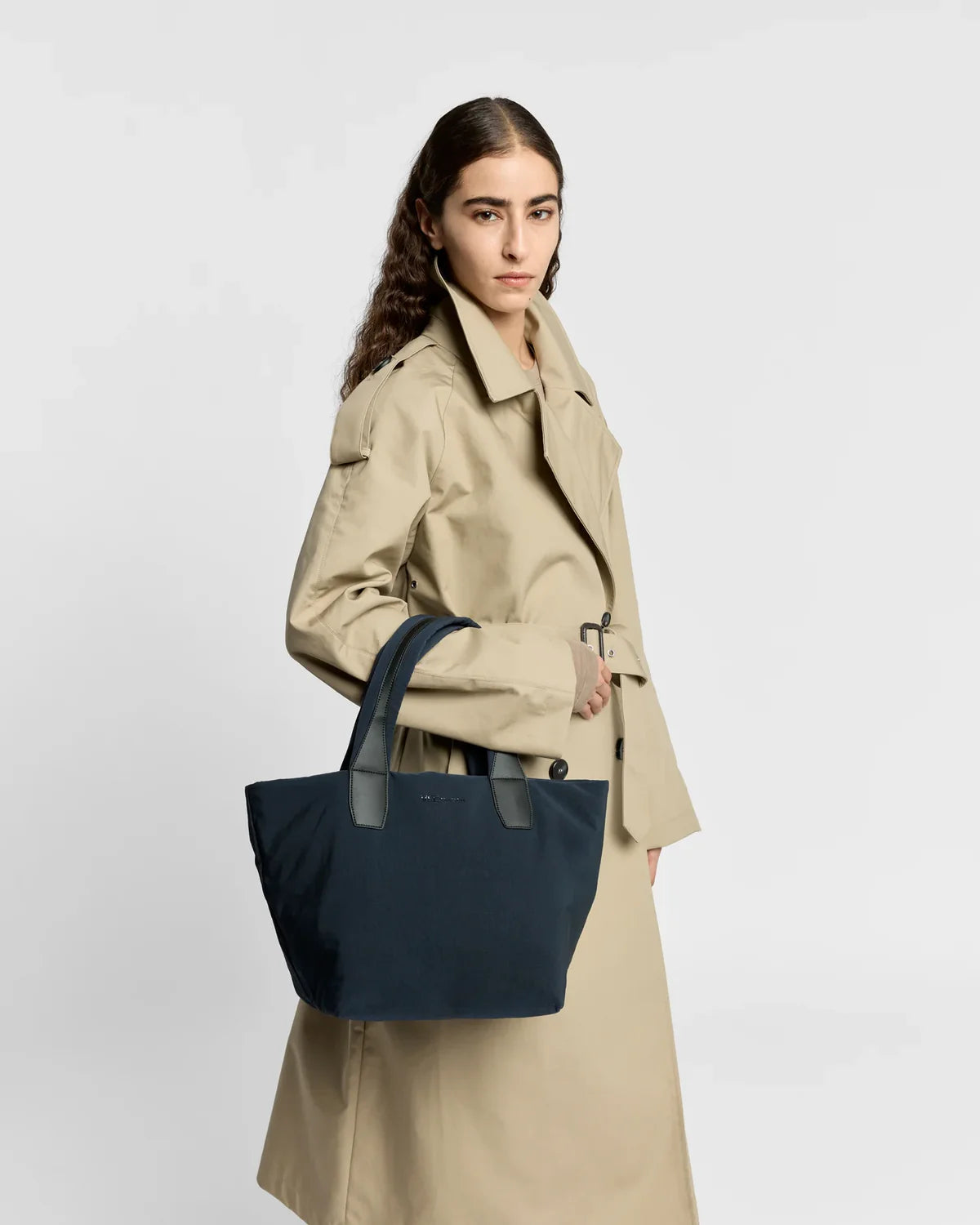 Woman holding a navy blue tote bag against a white background