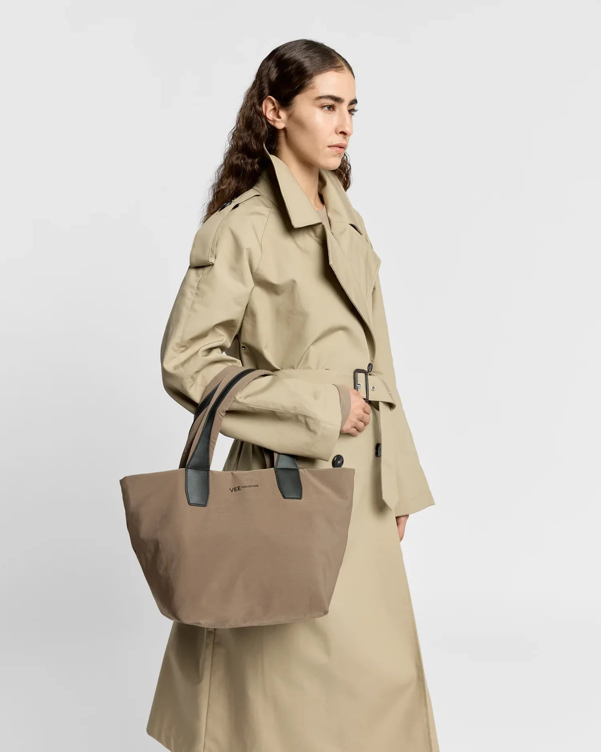 Woman holding a beige tote bag against a plain background