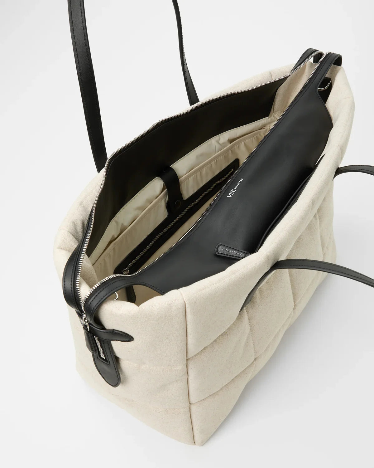 Beige tote bag with black interior and zipper on a white background