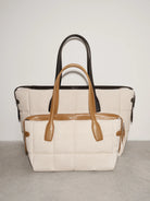Two handbags, one beige with brown handles and the other black with brown handles, on a light gray background.