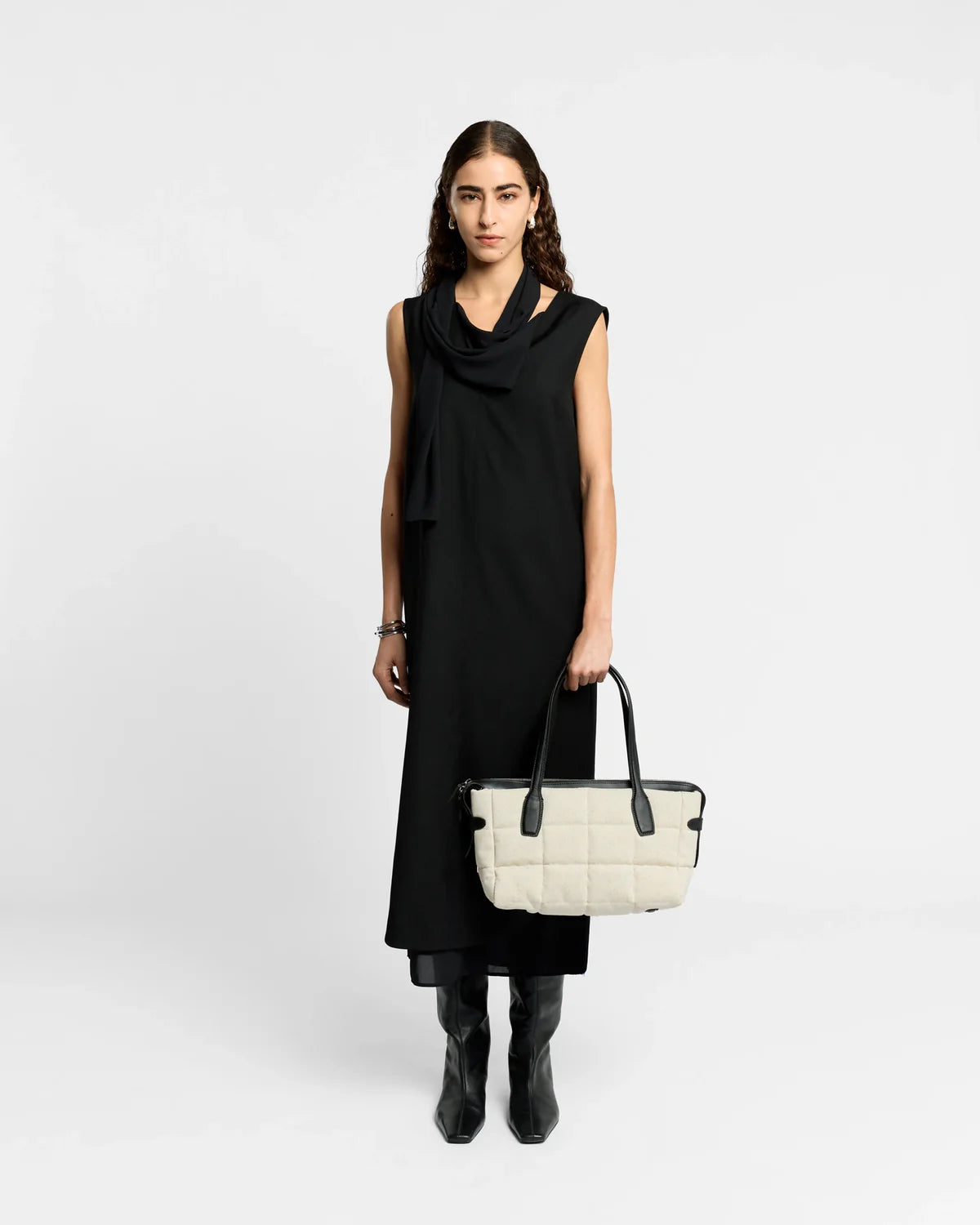 Woman holding a white handbag against a plain background
