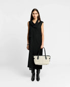 Woman holding a white handbag against a plain background