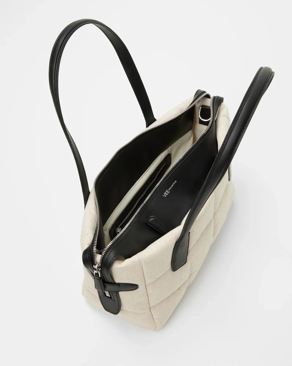 Beige handbag with black interior and handles on a light gray background