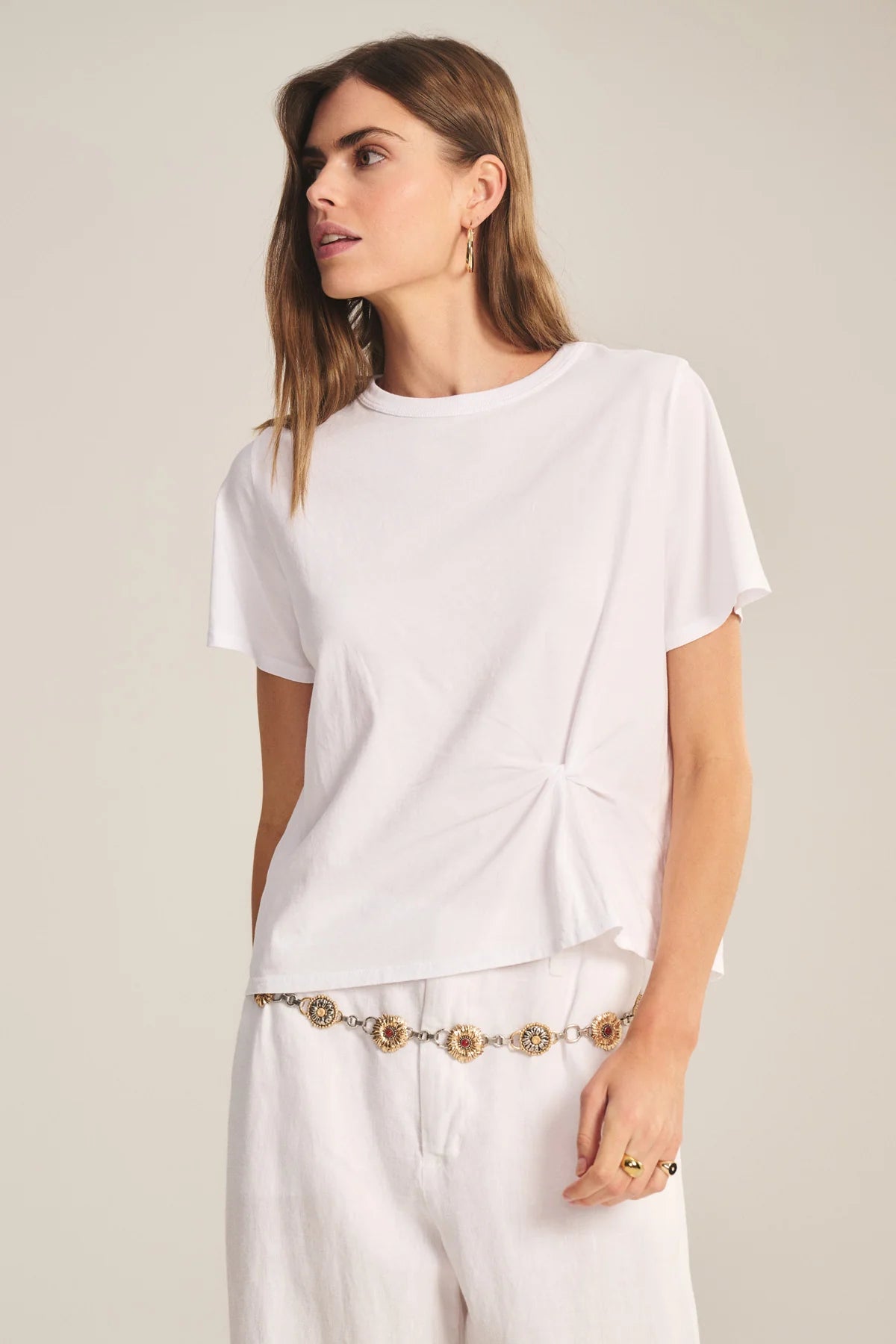 Woman wearing a white t-shirt and pants with a neutral background