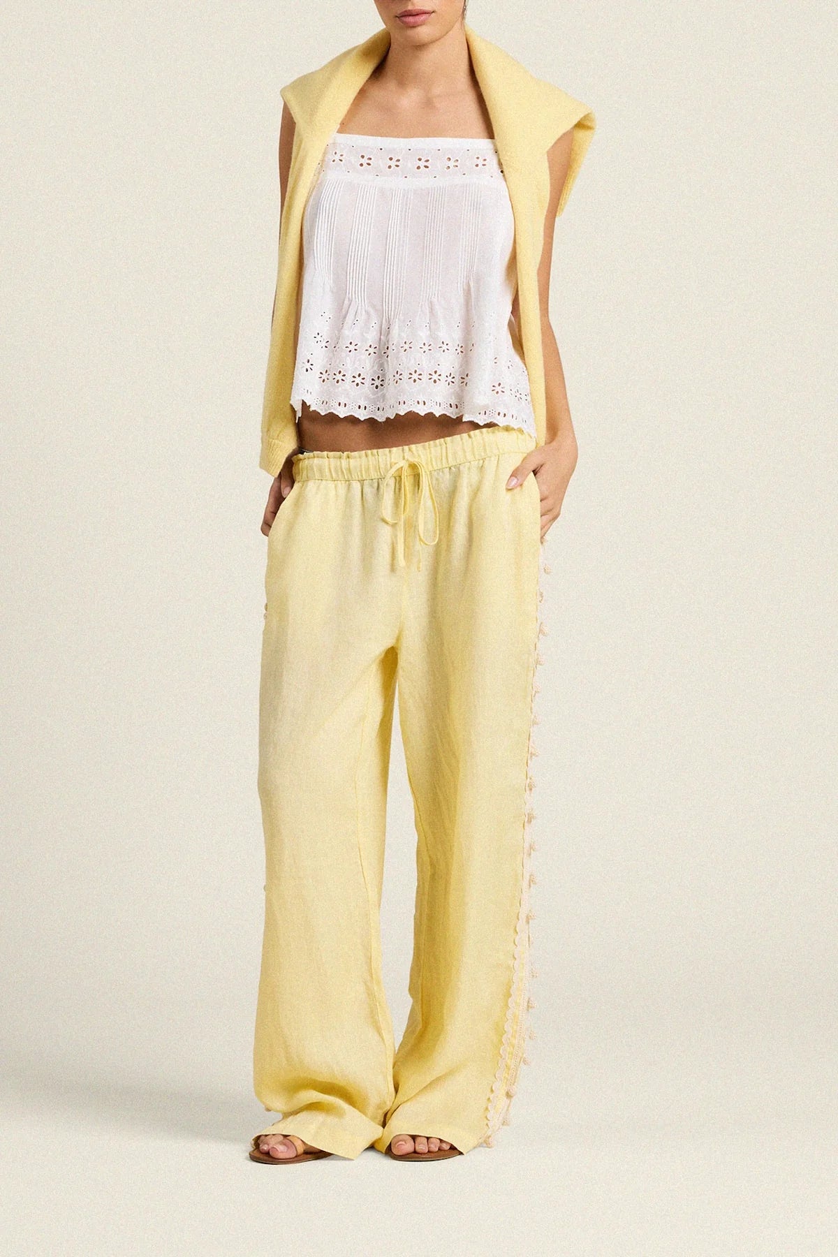 Woman wearing a yellow outfit with a white lace top on a beige background