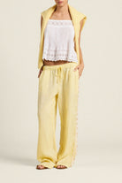Woman wearing a yellow outfit with a white lace top on a beige background