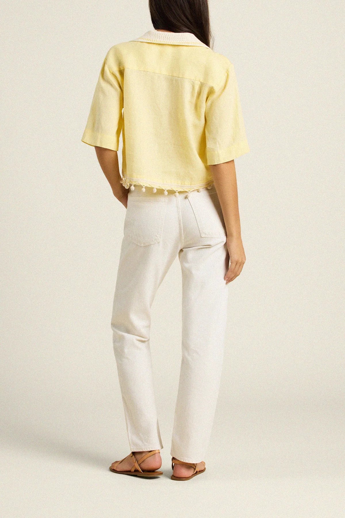 Person wearing a yellow top and white pants on a plain background