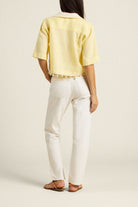 Person wearing a yellow top and white pants on a plain background